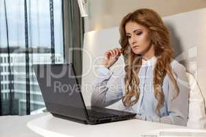 businesswoman using laptop while lying on bed