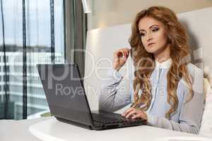 businesswoman using laptop while lying on bed
