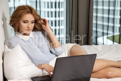 businesswoman using laptop while lying on bed