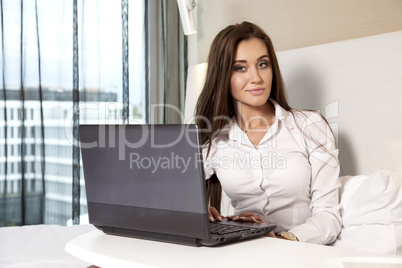 businesswoman using laptop while lying on bed