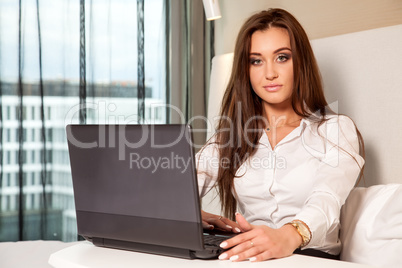 businesswoman using laptop while lying on bed