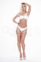 Sexy blonde woman wearing white swimwear posing on white backgro