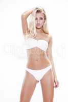 Sexy blonde woman wearing white swimwear posing on white backgro
