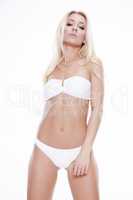 Sexy blonde woman wearing white swimwear posing on white backgro