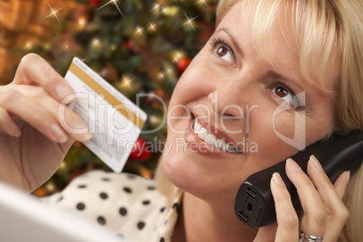 Phone Holding Woman Credit Card In Front of Christmas Tree