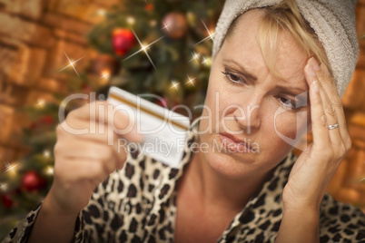 Upset Woman Holding Credit Card In Front of Christmas Tree