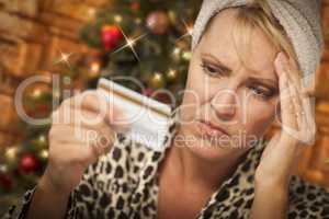 Upset Woman Holding Credit Card In Front of Christmas Tree