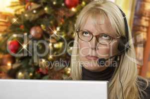 Upset Woman with Headset In Front of Christmas Tree and Computer