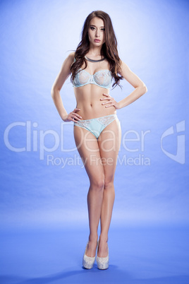 Young slim sexy woman in lingerie on blue background