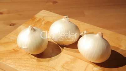 Three onions on a wooden board