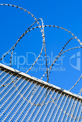 Fence with a barbed wire against the blue sky.