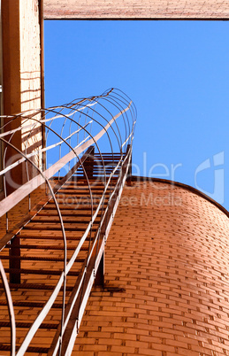 Industrial ladder, blue sky and brick walls of the building