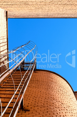 Industrial ladder, blue sky and brick walls of the building