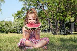 little girl sitting on grass and eat watermelon