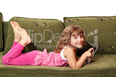 happy little girl lying on bed with tablet