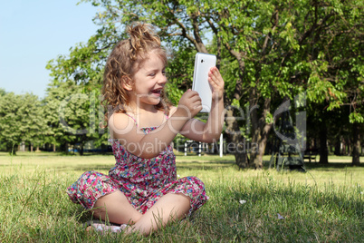 happy little girl with tablet in park