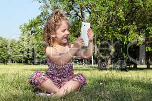 happy little girl with tablet in park
