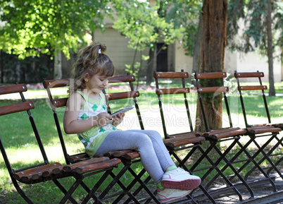 little girl with tablet sitting in park