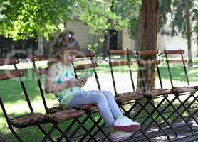 little girl with tablet sitting in park