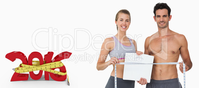 Composite image of sporty couple holding scales and measuring ta