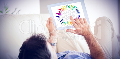 Composite image of man laying on sofa using a tablet pc