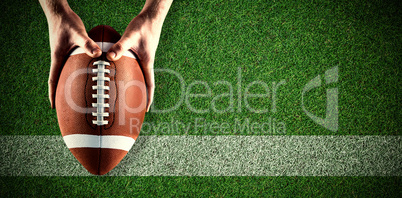 Composite image of american football player holding up football