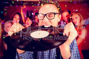 Composite image of geeky hipster biting vinyl record