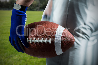 Composite image of cropped image of sportsman holding american football ball ball
