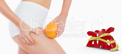 Composite image of woman squeezing fat on thigh as she holds ora