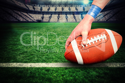 Composite image of american football player placing the ball