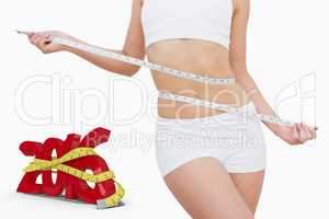 Composite image of slim woman measuring waist with tape measure
