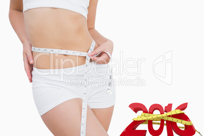 Composite image of fit woman measuring waist with measuring tape
