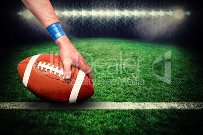 Composite image of american football player placing the ball