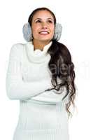 Smiling woman with earmuffs crossing arms and looking up