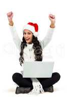 Woman sitting on the floor rejoicing looking at laptop