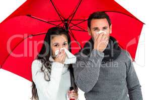 Couple under umbrella blowing their noses