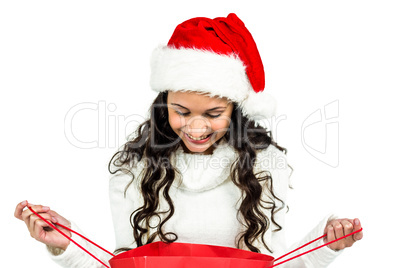 Happy woman with christmas hat looking in red shopping bag