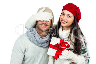 Smiling woman covering partners eyes and holding gift