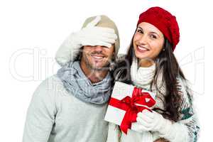 Smiling woman covering partners eyes and holding gift