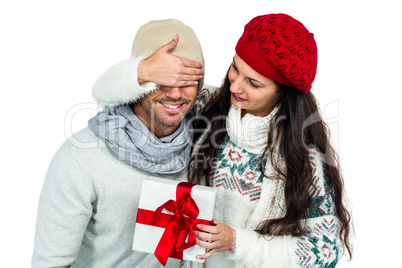 Smiling woman covering partners eyes and holding gift