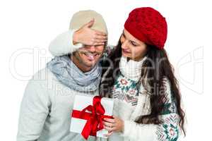 Smiling woman covering partners eyes and holding gift