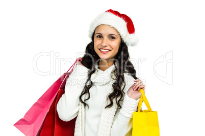 Smiling woman with christmas hat holding colored shopping bags