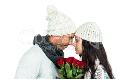 Smiling couple nose-to-nose holding roses bouquet