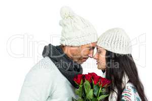Smiling couple nose-to-nose holding roses bouquet
