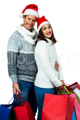 Festive couple smiling and holding gift bags