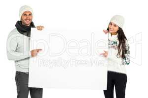 Smiling couple holding and pointing white sheet