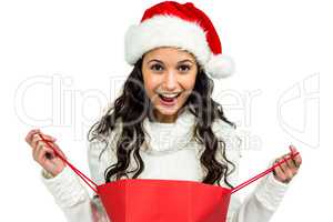 Happy woman with christmas hat opening red shopping bag