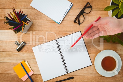 Composite image of hand holding red pencil