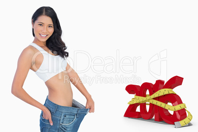 Composite image of cheerful woman holding her too big pants