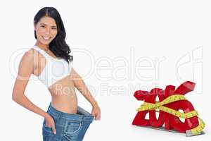 Composite image of cheerful woman holding her too big pants